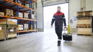 Linde Techniker - Service für Ihren Gabelstapler Ein Techniker von Linde Material Handling läuft durch ein Lager