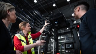 Drei Personen stehen vor einem automatisierten Fahrzeug von Linde MH.