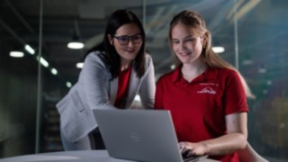 Zwei Personen sitzen vor einem Laptop.