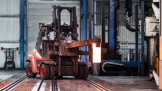 Das Gerät transportiert ein glühendes Eisen über das Gelände.