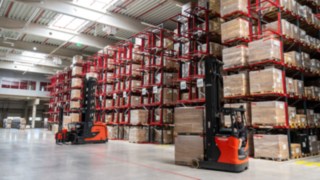 Linde Schmalgangstapler und Schubmaststapler vor einem Palettenregal