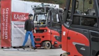 Dank ultraschnellem privaten 5G-Netz und stationären 3D-Laserscannern werden Kollisionen zwischen autonomen Staplern und Personen verhindert. Ein Crashtest-Dummy ist zwischen autonomen Linde-Staplern aufgestellt.