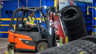 Mitarbeiter von Michelin Tyre PLC greift einen Reifenstapel mit einer am Gabelstapler montierten Klammer.