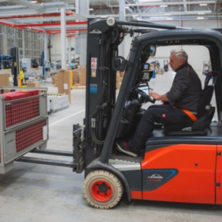 Ein Linde Elektrostapler transportiert eine Gitterbox