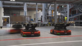 Drei Autonome Mobile Roboter (AMR) von Linde MH fahren durch das Lager