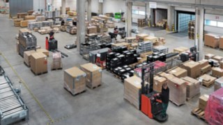 Logistiklager von Simon Hegele mit Mitarbeitern, die Paletten mit Waren sortieren und transportieren.