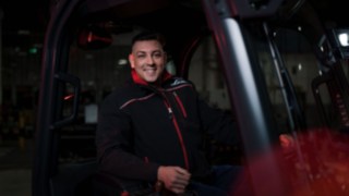 Mitarbeiter von Linde Material Handling sitzt in einem Flurförderzeug und lächelt in die Kamera.