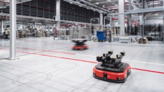 Autonome Transportroboter in einer modernen Logistikhalle stehen für Spitzentechnologie, intelligente Automatisierungslösungen und die innovative Unternehmenskultur bei KION.