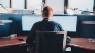 Ein Linde-Mitarbeiter entwickelt modernste Automatisierungslösungen bei KION Automation, indem er mit CAD-Software an zwei Monitoren arbeitet. 