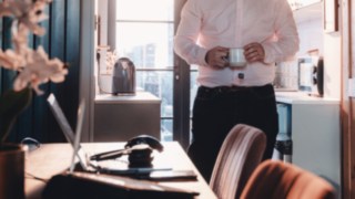 Eine Person arbeitet im Homeoffice mit einer Kaffeetasse in der Hand und repräsentiert die flexiblen Arbeitszeiten und eine gesunde Work-Life-Balance bei KION Automation. 