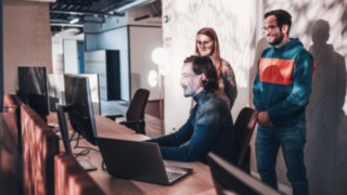 Ein dynamisches Team arbeitet am Arbeitsplatz zusammen und zeigt gelebte Kooperation und Teamspirit bei KION Automation. 