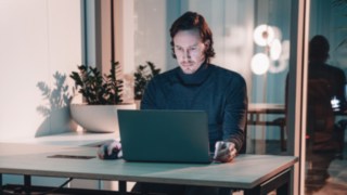Ein Projektmanager arbeitet konzentriert an einem Laptop in modernem Büroambiente, was für eigenverantwortliches Arbeiten, globale Teamkoordination und verlässliche Netzwerke im internationalen Projektmanagement steht. 