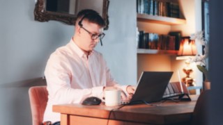 Ein Mitarbeiter arbeitet konzentriert im Homeoffice an einem Laptop; moderne Technik, eine gemütliche Umgebung und flexible Arbeitsbedingungen ermöglichen eine ausgewogene Work-Life-Balance bei KION. 