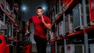 Ein Mann in Sportkleidung rennt in einem Lagergang.