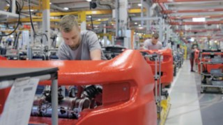 Unser Plattformkonzept mit Mix-Montage ermöglicht effiziente Ressourcenschonung. Eine Reihe von Werksmechanikern arbeiten an Linde Fahrzeugen.